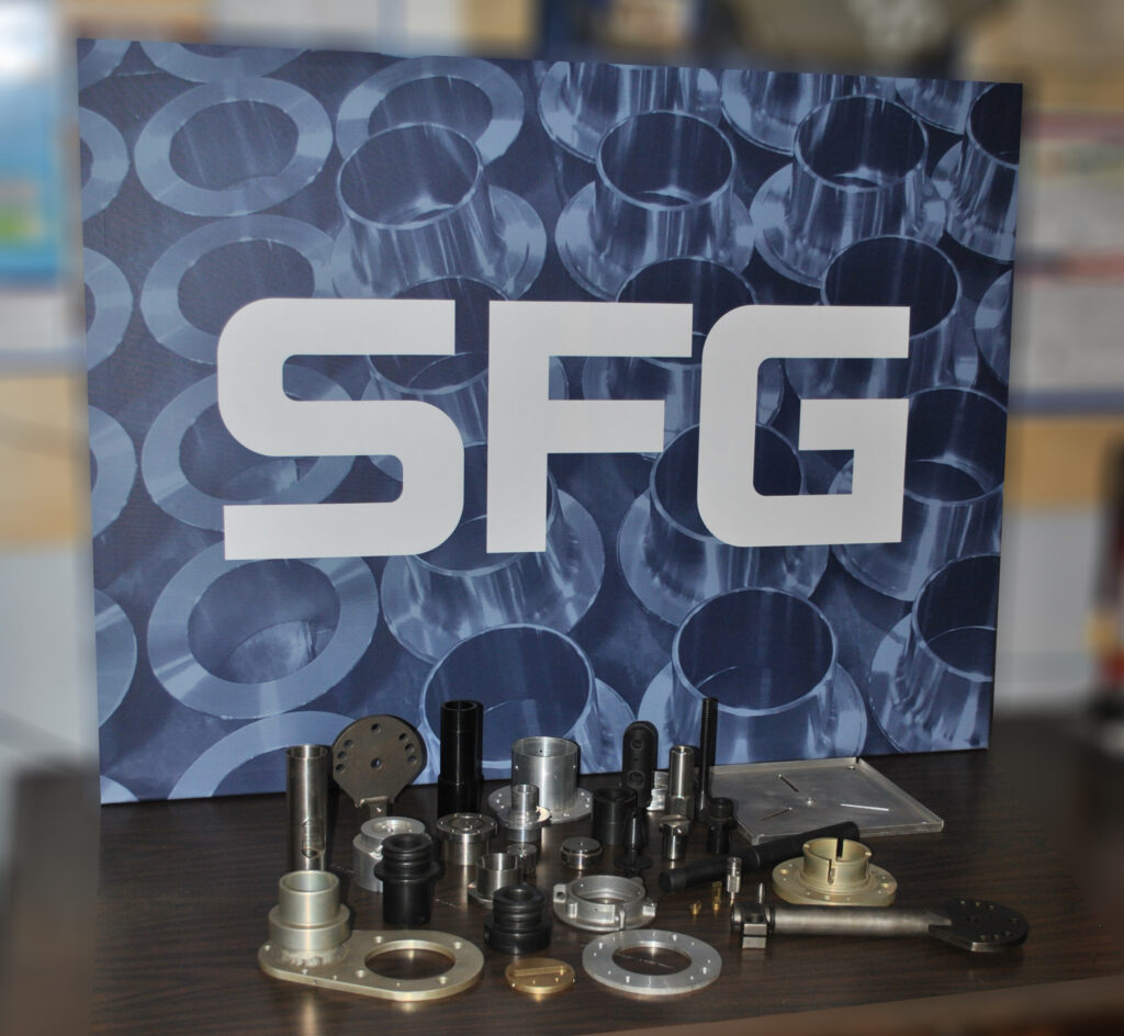 Stainless steel machined parts in front of an SFG logo background.